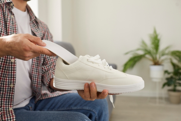 Mann legt Einlage in den Schuh ein.