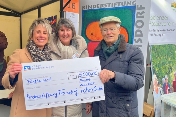 Meike Rahm überreicht Andrea Schrahe von der Kinderstiftung Troisdorf einen Scheck über 5.000 Euro.