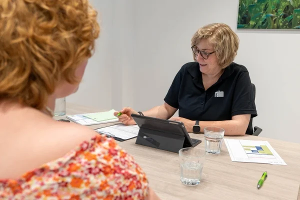 Eine Mitarbeiterin berät in persönlicher Atmosphäre Kundin zu neurologischen Erkrankungen.